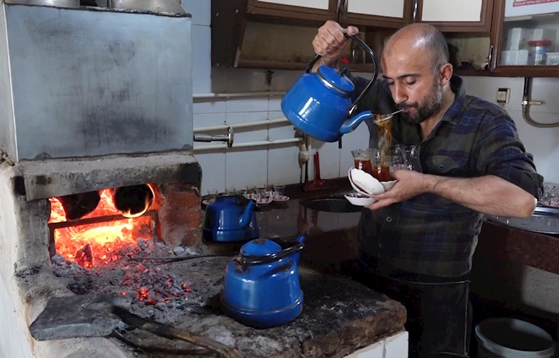 Çay taleplerine yetişmek için ağzında süzgeçle bardakları dolduruyor